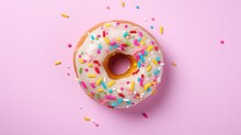  A Donut With White Frosting And Sprinkles On A Pink Background With Colored Sprinkles.