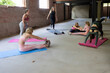 © Bjorn B - This image shows a diverse group of women each absorbed in different aspects of physical fitness. One performs a seated stretch, another squats, a pair work on core strengthening with sit-ups, and one