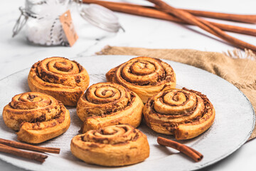 Wall Mural - Homemade cinnamon rolls on white plate on white marble background