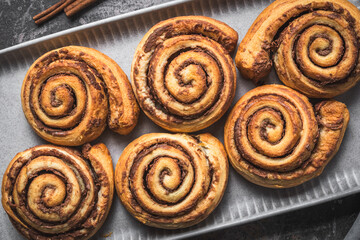 Wall Mural - Closeup of homemade cinnamon rolls on a gray earthenware tray on gray background