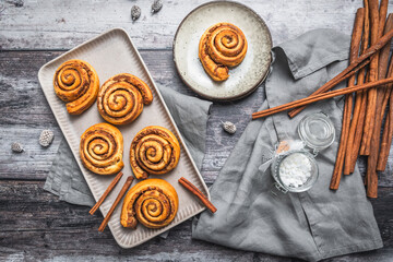 Wall Mural - Homemade cinnamon rolls on a gray earthenware tray on gray background