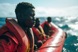 African migrants and refugees sit on a rubber boat on the sea.