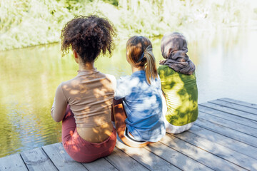 Wall Mural - Rear view of multiracial young teen female friends resting in the park