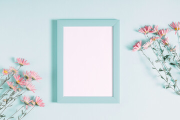 Wall Mural - beautiful flowers composition. light pink flowers, empty photo frame for text on pastel blue backgro