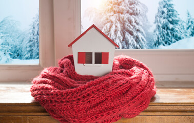 Wall Mural - house in winter - heating system concept and cold snowy weather with model of a house wearing a knitted cap. High quality photo