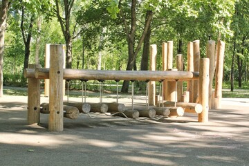 Wall Mural - Wooden playground made of natural eco-friendly material in public city park. Modern safety children outdoor equipment. Concept of sustainable lifestyle and ecology. Children rest and games on open air