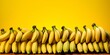 several ripe bananas stacked on top of each other in front of a yellow background