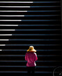 One woman wearing yellow hat walking up the public stairs in sunlight and shadows