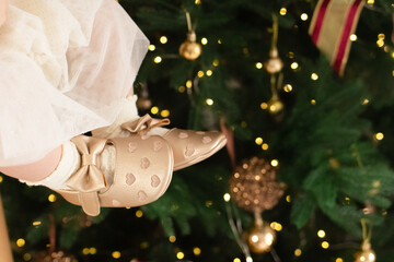 legs of a little girl in golden shoes against the background of a Christmas tree. christmas and new year concept