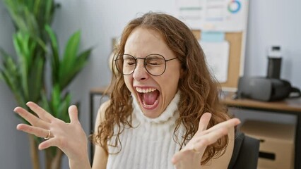 Wall Mural - Excited young woman in office, celebrating her crazy, mad win. arms raised in triumph, she's the beautiful working winner!