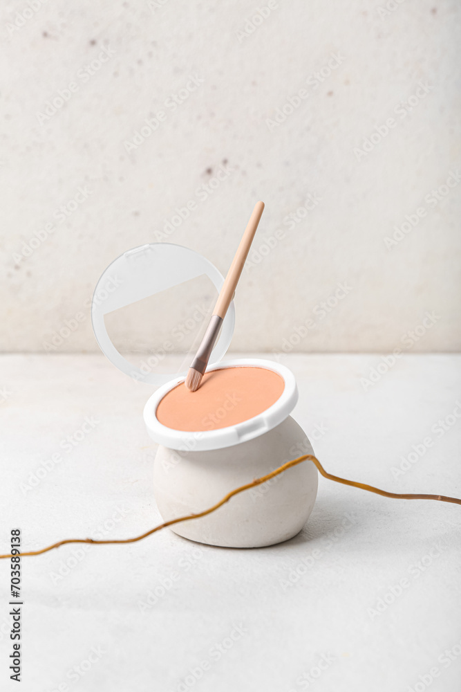 Decorative plaster podium with powder, brush and tree branch on white table