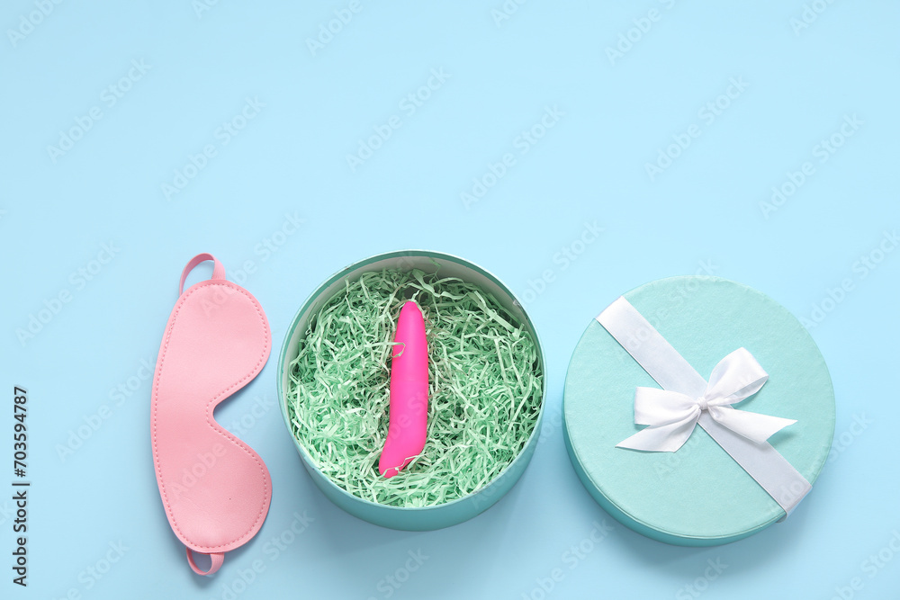 Gift box with vibrator and mask on blue background