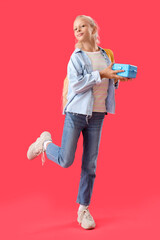 Poster - Happy girl with backpack and lunchbox on red background