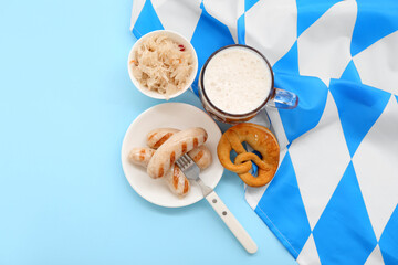 Tasty sausages, sauerkraut, flag of Bavaria, pretzel and mug with beer on blue background. Oktoberfest celebration