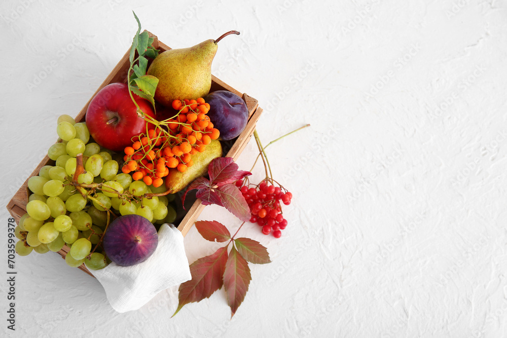 Wooden box with different fresh fruits and berries on white background