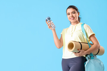 Sticker - Young woman with water bottle and fitness mat on blue background