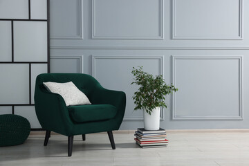 Sticker - Stylish armchair with pillow and houseplant on floor near light grey wall indoors, space for text. Interior design