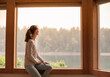 © kieferpix - Young woman looking out window early morning
