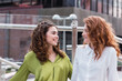 © BUDDHA - Two trendy businesswomen talking and laughing casually outside