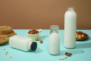 Wall Mural - Raw mixed nuts are displayed on blue surface with few bottles of milk. Soybean (Glycine max) extract is used in a wide range of skincare products