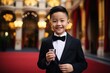 happy asian boy in suit and bow tie with coffee cup on red carpet