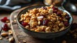 Homemade granola with nuts and dried cranberries in a bowl on a wooden background.