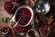 Cranberry sauce in ceramic saucepan with ingredients for cooking on kitchen wooden table top view