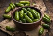 Pickled gherkins or cucumbers in bowl on wooden rustic table from above