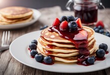 Stack Of American Pancakes Or Fritters With Strawberry And Blueberry Jam In White Plate On Wooden