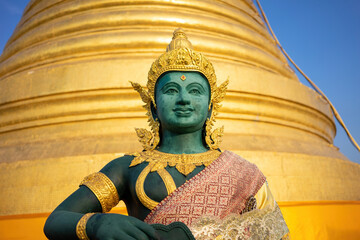 Serene Deity Sculpture in Traditional Attire - An exquisite statue against a golden stupa, symbolizing spiritual reverence and cultural heritage