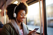Happy young African American woman passenger listening music via smart mobile phone in a train, Smile female wearing wireless headphones while moving in the tram, lifestyle, transportation. Generative