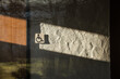 Symbol Rollstuhlfahrer an Toiletten-Holztüre und verputzter Wand mit Schattenspiel mit starkem Hell-Dunkel Kontrast       