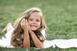 © Irina Mikhailichenko - Cute little girl in white dress is lying on the grass on warm summer day. Relax and vacation concept.
