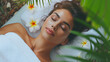 smiling woman lying on her back on white towel, relaxing and resting in a spa, her eyes closed