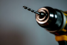 Electric drill, screwdriver with a dull metal drill bit close up shot, space for text.