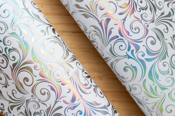 Sticker - rolled or curled decorative iridescent scrapbooking paper with floral or decor pattern background on wood