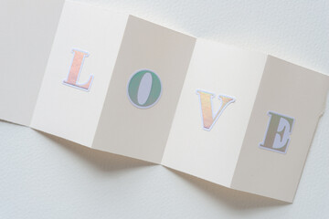 Sticker - fan folded blank cards with sticker letters composing the word love and arranged on blank paper