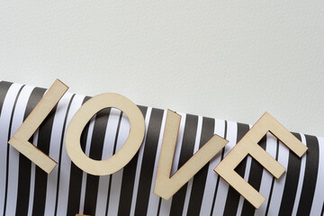 Poster - trendy sign with wood letters, or the word love balancing on a sheet of paper with black and white stripes