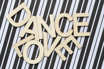 Poster - trendy sign with wood letters, or the words dance and love on a backdrop of paper with black and white stripes