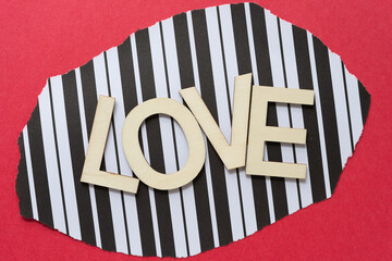 Sticker - trendy sign with wood letters, or love on a black and white striped paper backdrop on red