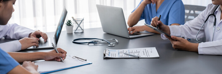 Doctor and nurse in medical meeting discussing strategic medical treatment plan together with report and laptop. Medical school workshop training concept in panoramic banner. Neoteric