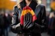 Close up of a woman in a black leather jacket holding a folded Spanish flag