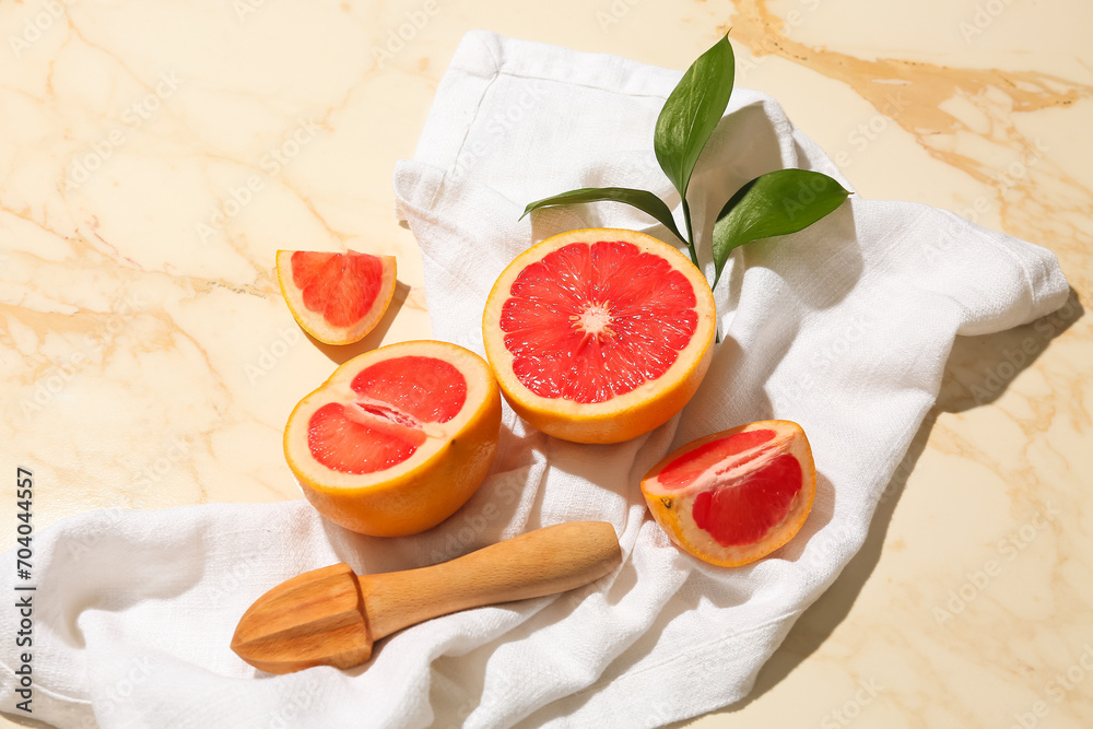 Composition with cut ripe grapefruits, juicer and plant branch on light background
