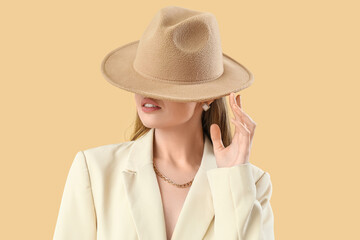 Poster - Fashionable young woman in stylish jacket and hat on beige background