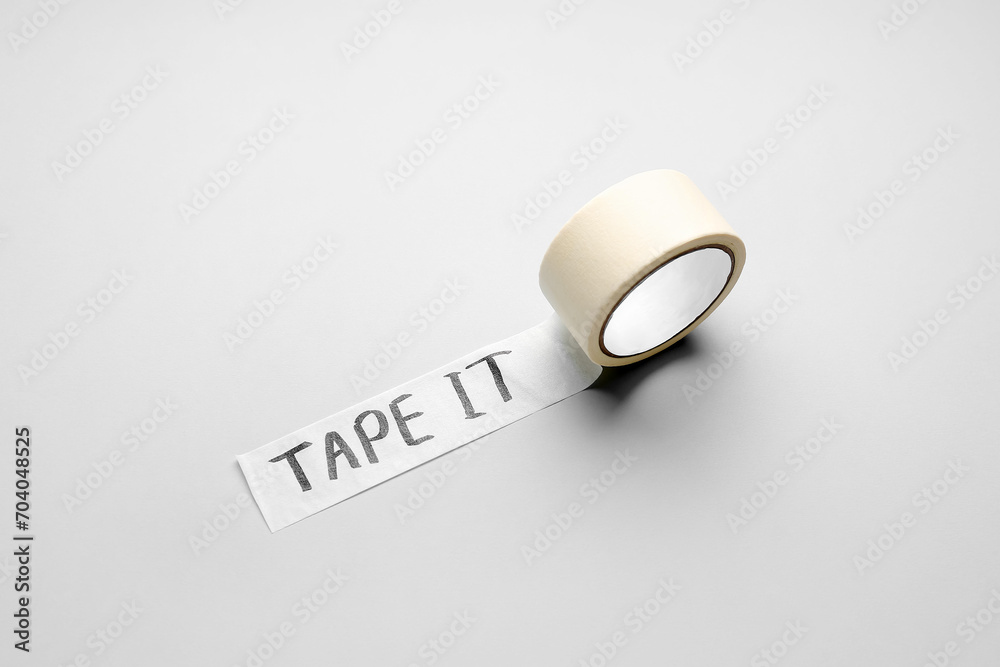 Adhesive tape roll with text TAPE IT on grey background