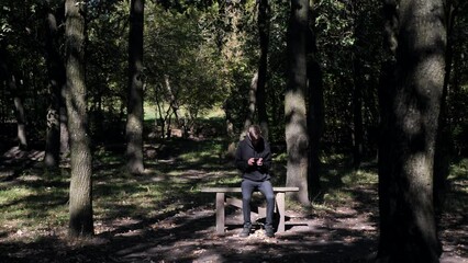 boy playing on the phone while sitting on a bench in the forest.Copy space.place for text