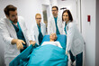 Professional team of surgeon, doctors and nurse moving unconscious patient on a gurney to the emergency operating room.