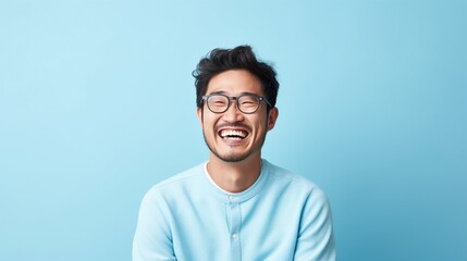 Wall Mural - A young Asian man wearing glasses is laughing.