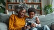 selective focus on grandson teaches grandmother to use a mobile phone, sitting together on the sofa in a close-up shot