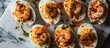 Deviled eggs with shrimp on a marble table, viewed from the top.